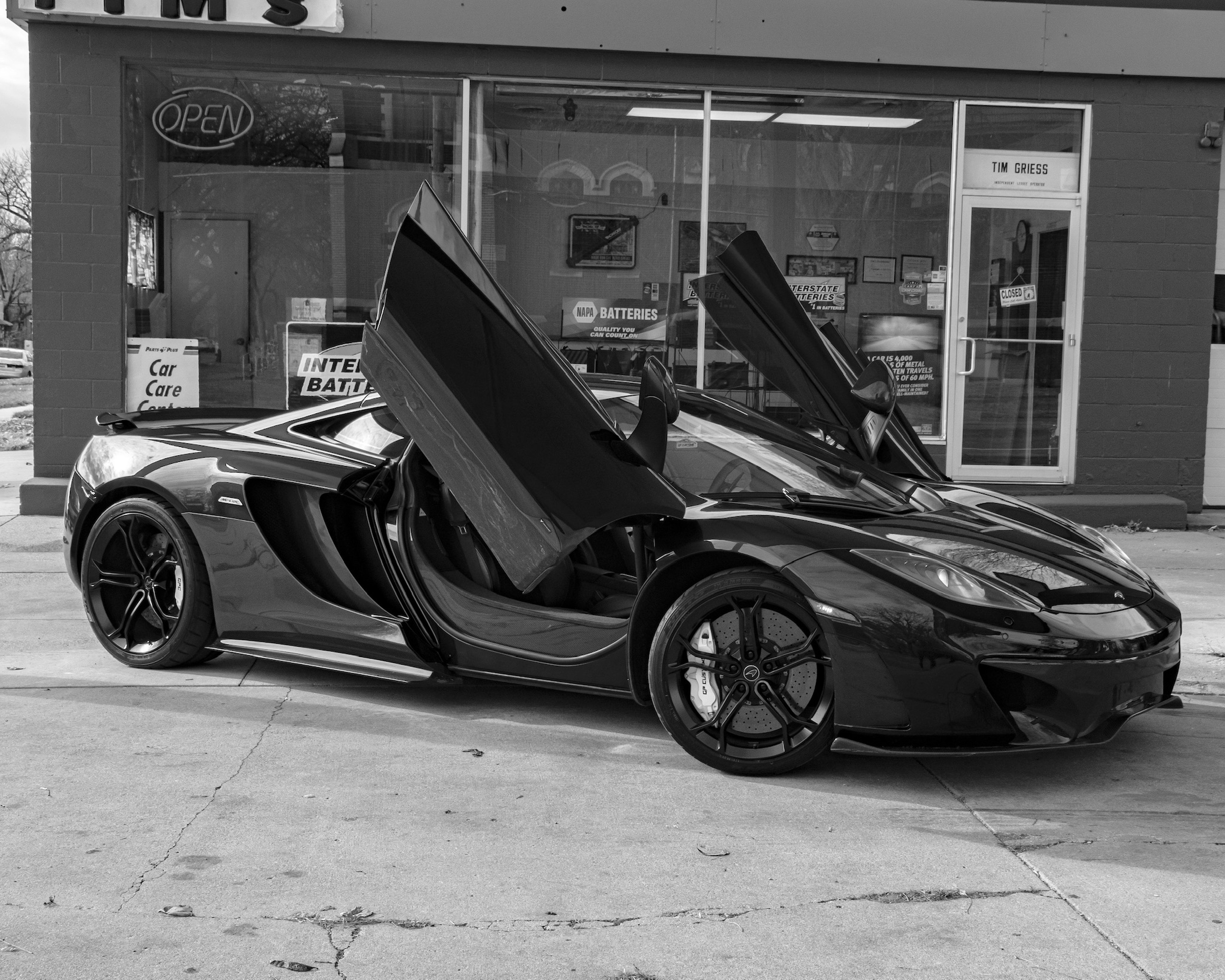 grayscale photo of car parked beside building